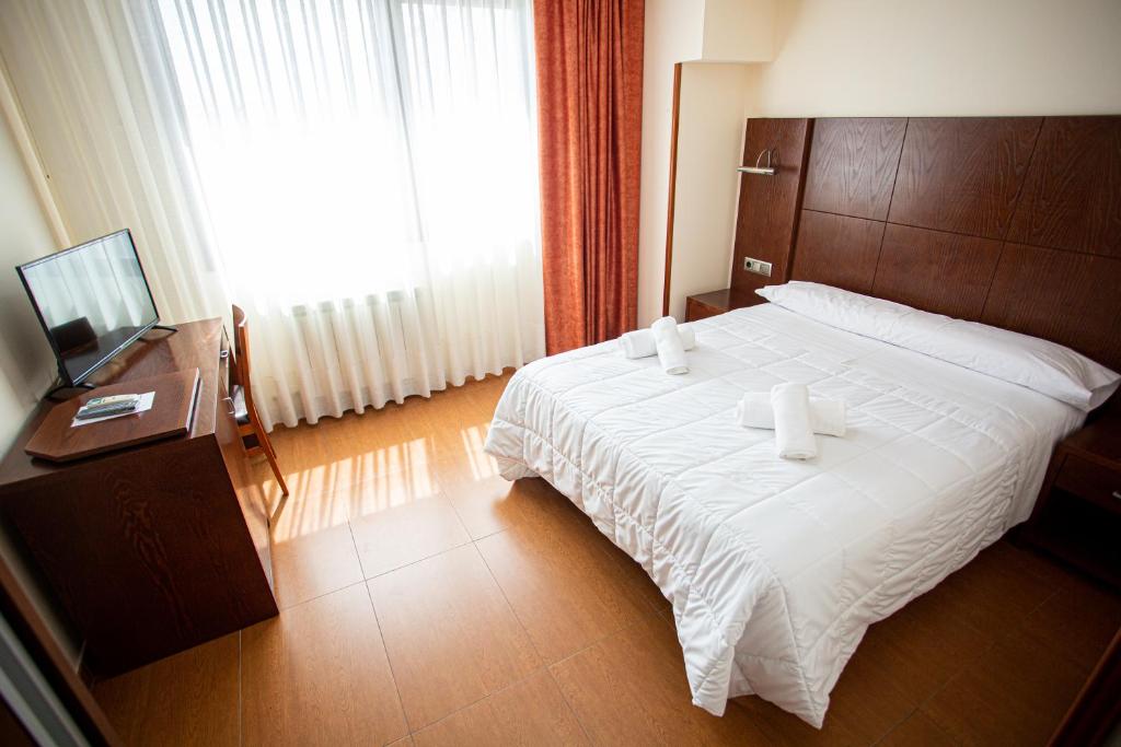 Hotel Villa De Cárcar في Cárcar: غرفة نوم بسرير كبير وتلفزيون