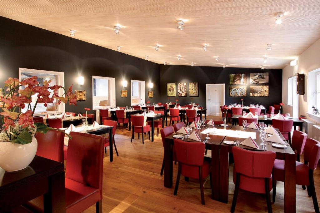 a dining room with tables and red chairs at Heidehotel Gut Landliebe in Hermannsburg