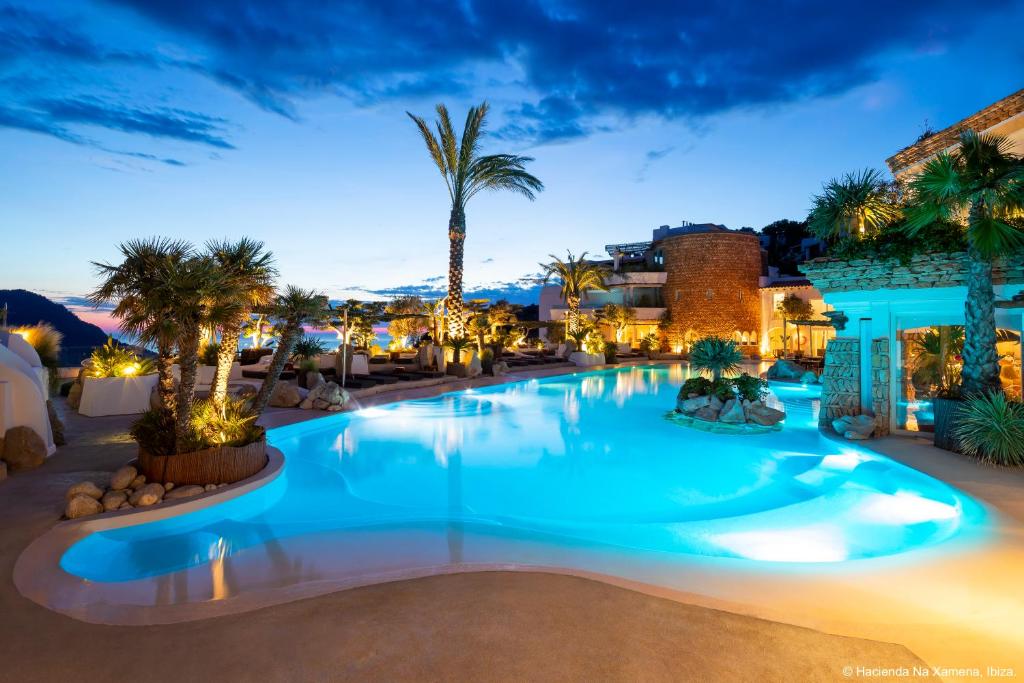 basen w nocy z palmami i budynkami w obiekcie Hacienda Na Xamena, Ibiza w mieście Na Xamena