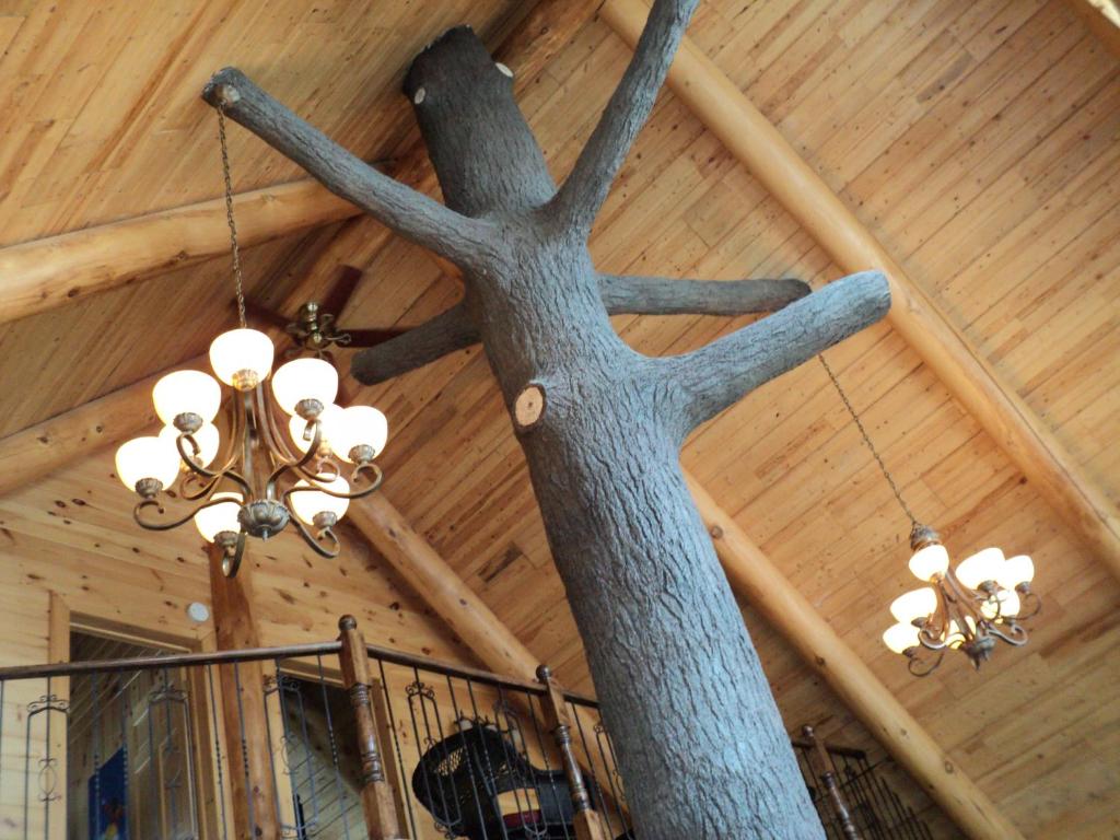 a chandelier hanging from a wooden ceiling with a tree branch at Le Chalet Bois Rond Relax in Saint-Tite-des-Caps