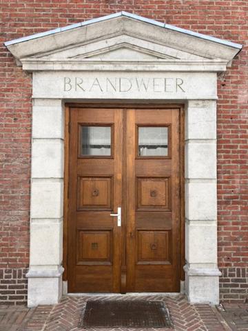 una gran puerta de madera en un edificio de ladrillo en De Oude Kazerne Torenkamer, en Kaatsheuvel