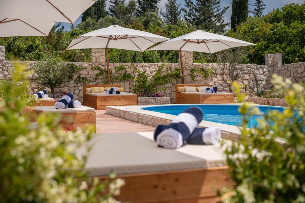 a teddy bear laying on beds next to a swimming pool at Kis Residence - Adults Only in Korčula