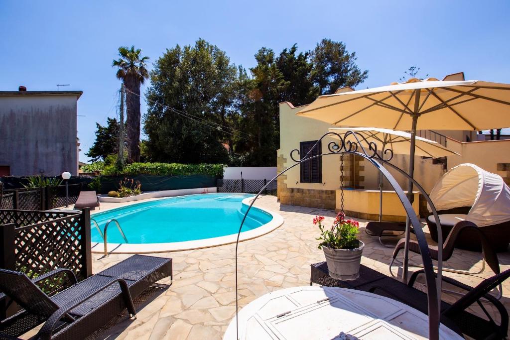 una piscina con ombrellone accanto a una casa di Top Sea Ognina a Ognina