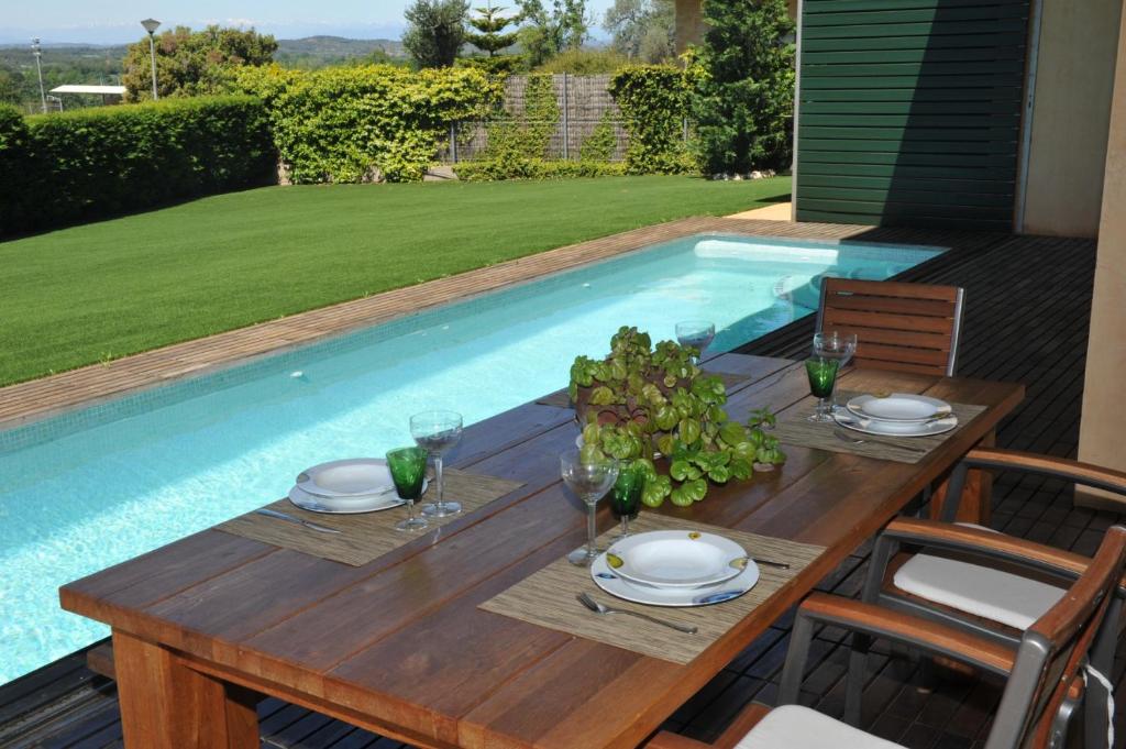 een houten tafel met borden naast een zwembad bij CASA LLEVADORA in Pals