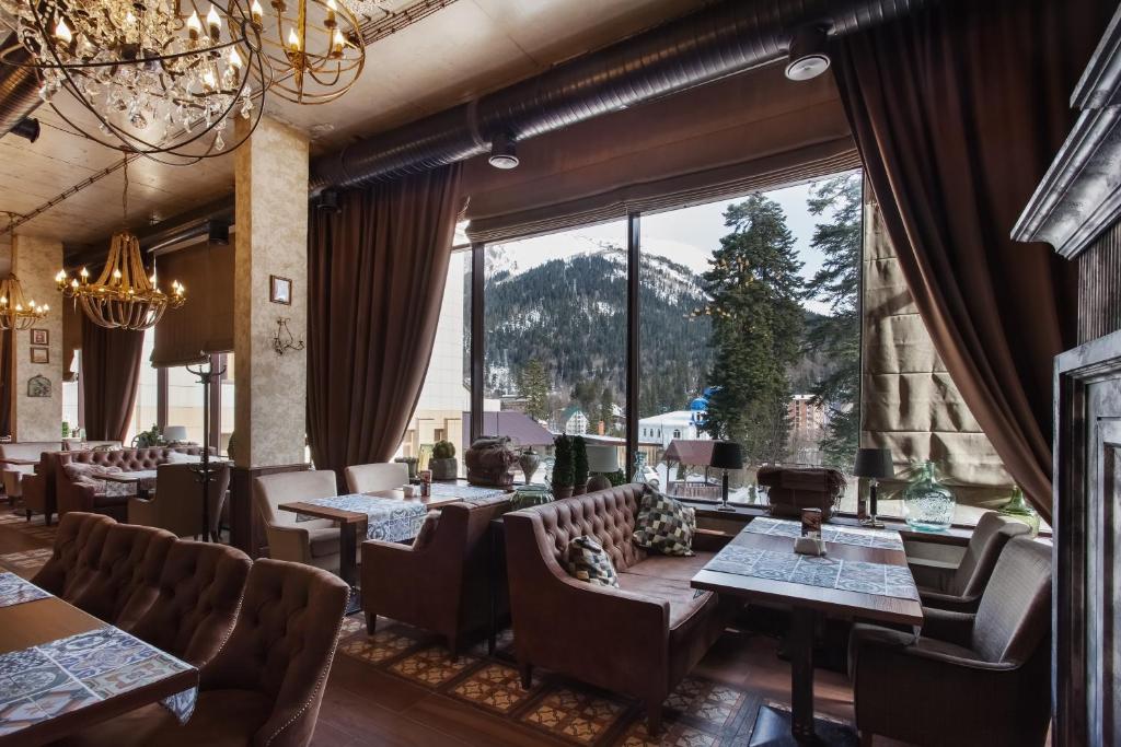 ein Restaurant mit Tischen und Stühlen und einem großen Fenster in der Unterkunft Andersen Hotel in Dombai