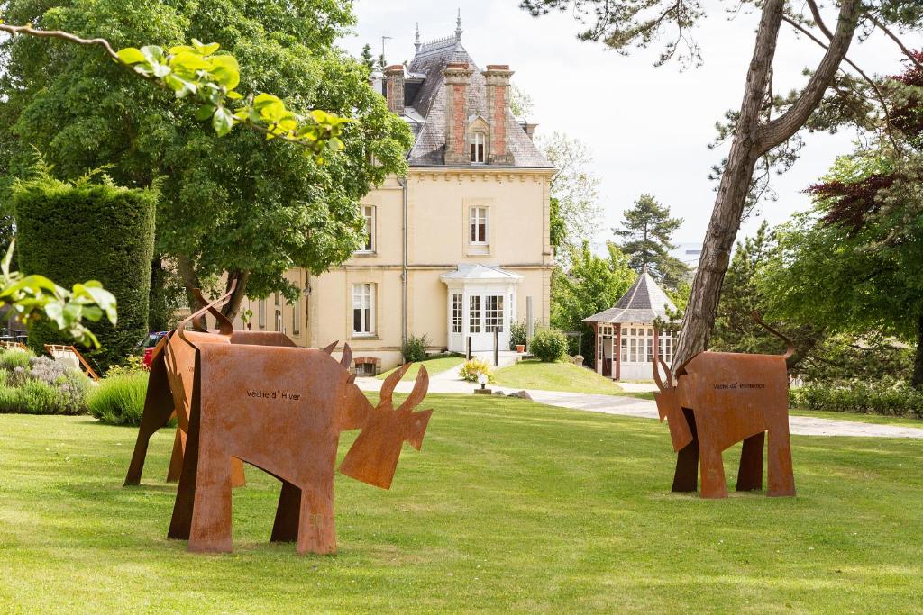 twoulptures of elephants in the grass in front of a house at Les Villas d'Arromanches, Teritoria in Arromanches-les-Bains