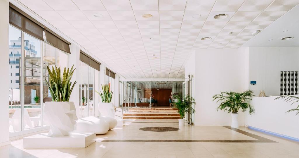 a lobby with white furniture and plants in a building at Hotel Safari in Gandía