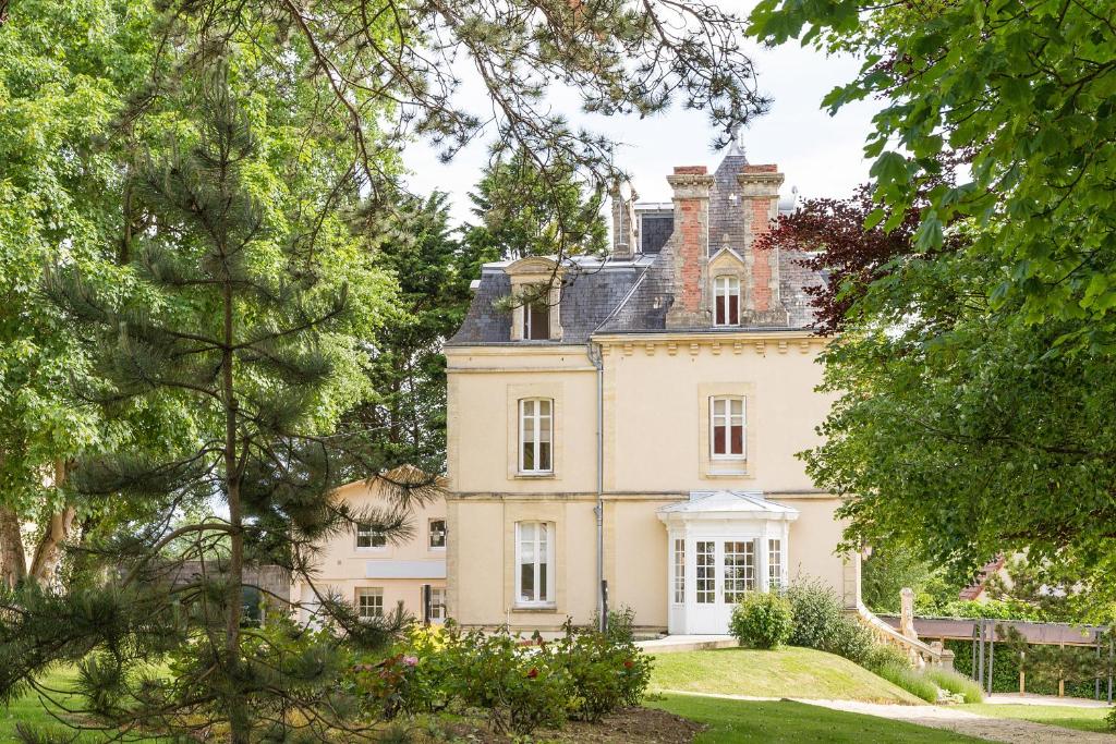 a large house with trees in front of it at Les Villas d'Arromanches, Teritoria in Arromanches-les-Bains