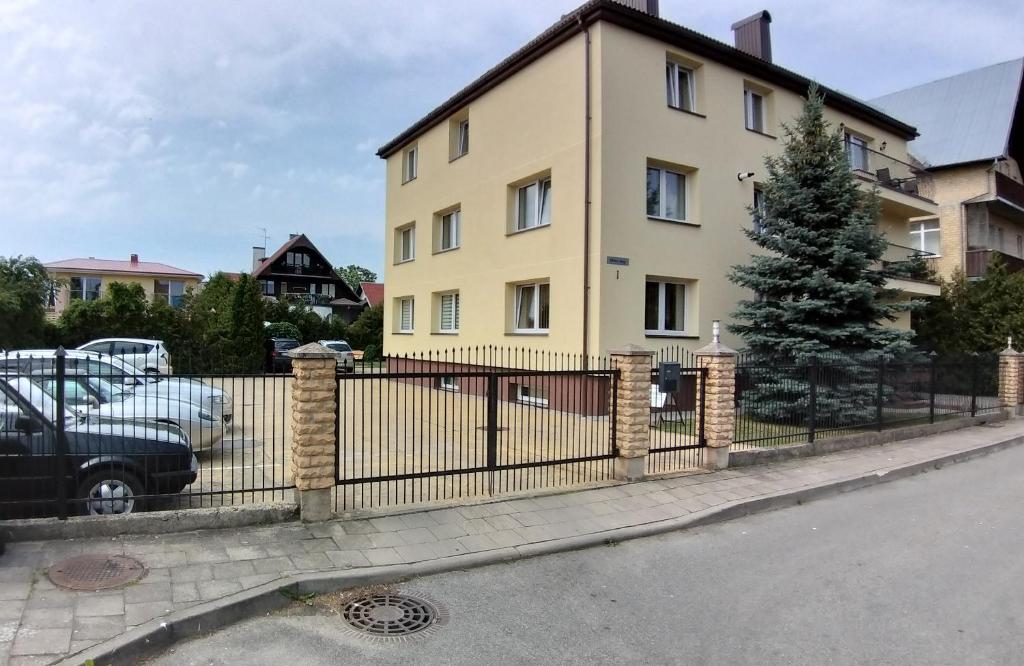 a fence in front of a yellow building at Poilsis Palangoje pas Daivą in Palanga