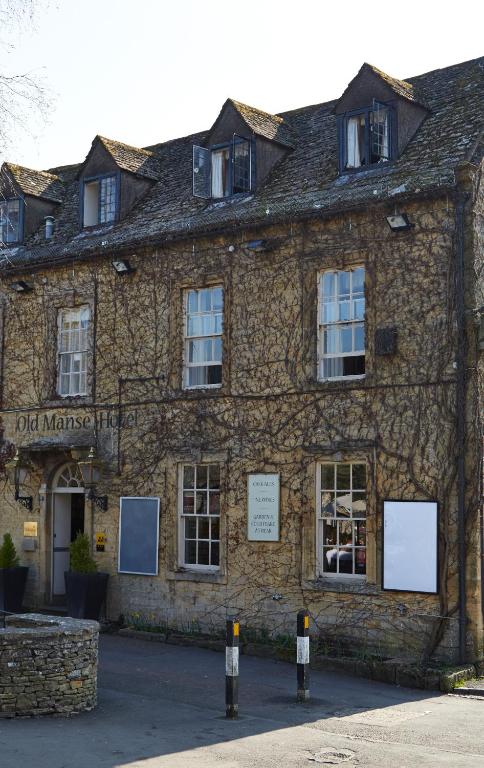 an old stone building with two parking meters in front of it at Old Manse Hotel by Greene King Inns in Bourton on the Water