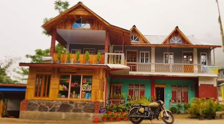 a house with a motorcycle parked in front of it at VAMOOSE YOLMO in Mirik