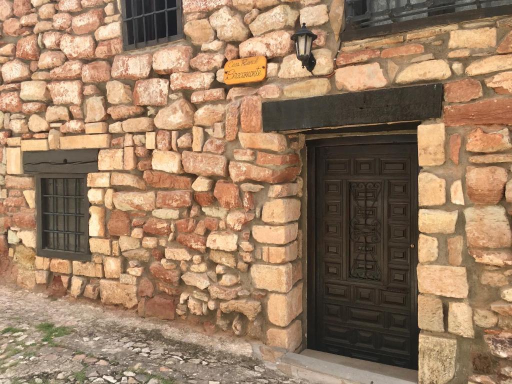 a stone building with a wooden door and two windows at Casa Rural Bracamonte in Alcaraz