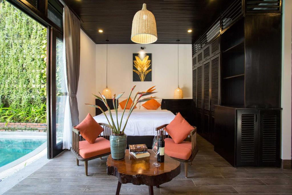 a bedroom with a bed and a table with chairs at MAI Villa Da Nang in Danang