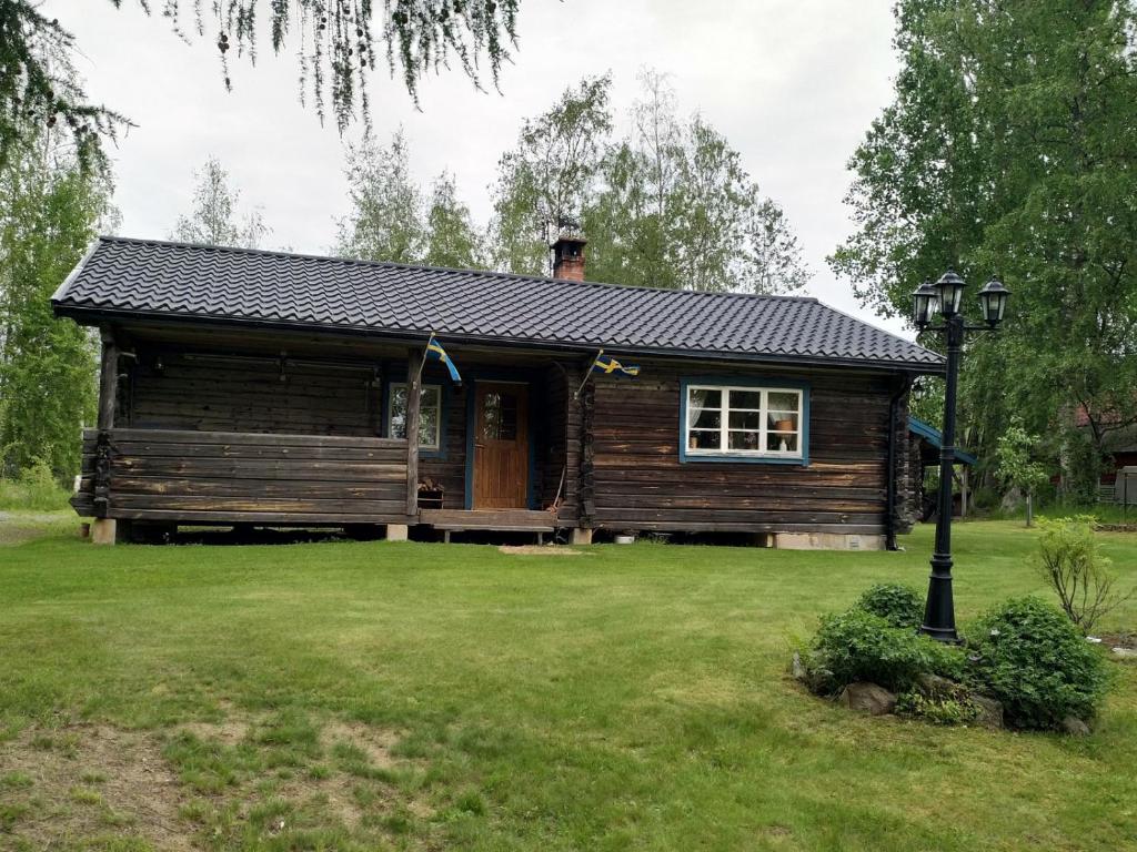 una cabaña de madera en un patio con césped verde en Mysig timmerstuga vid sjön Björken en Grangärde