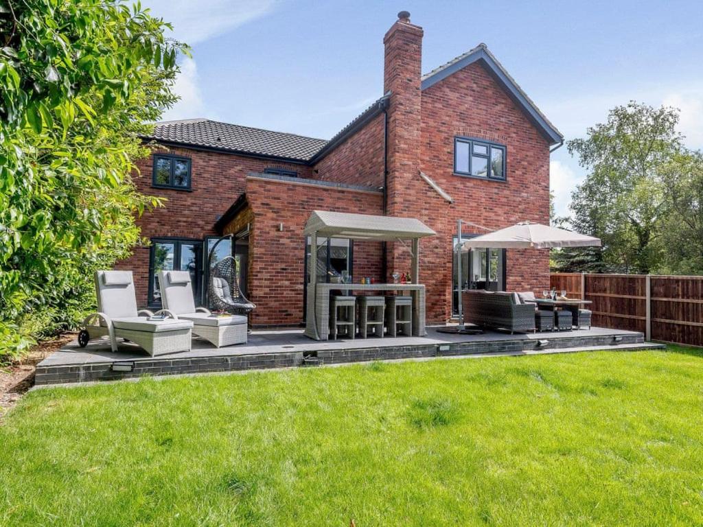 a brick house with a patio and lawn at Kingfisher Lodge - 4 Bed Villa in Horning