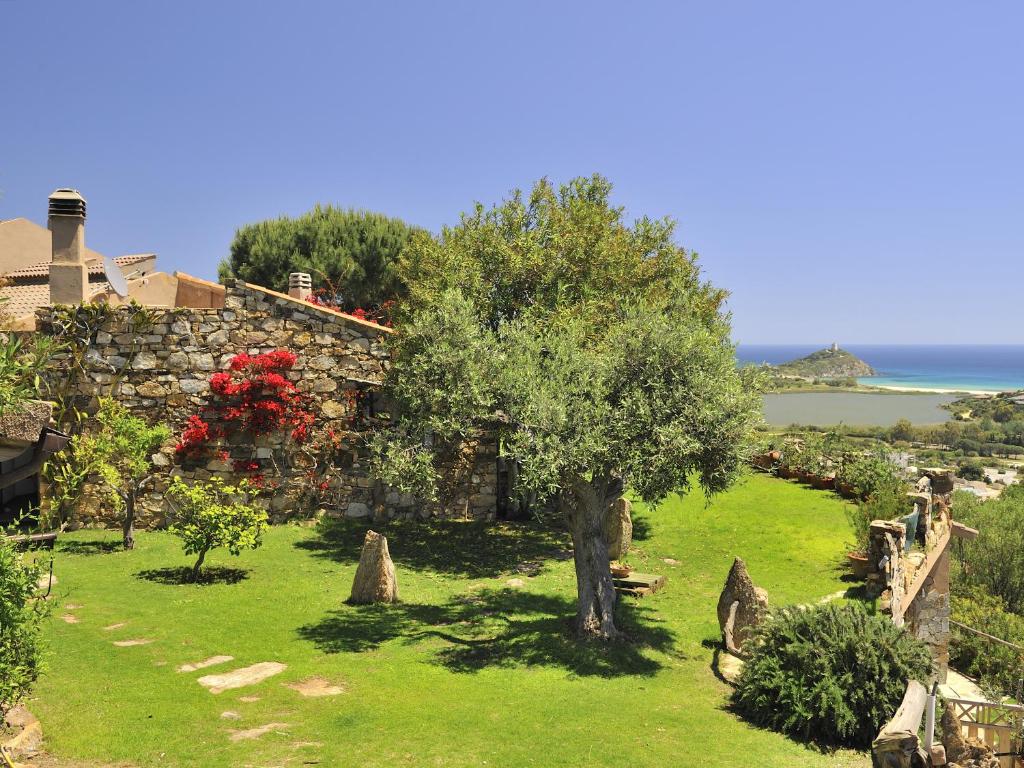 a garden with a tree and a stone building at Villa Ibisco in Chia