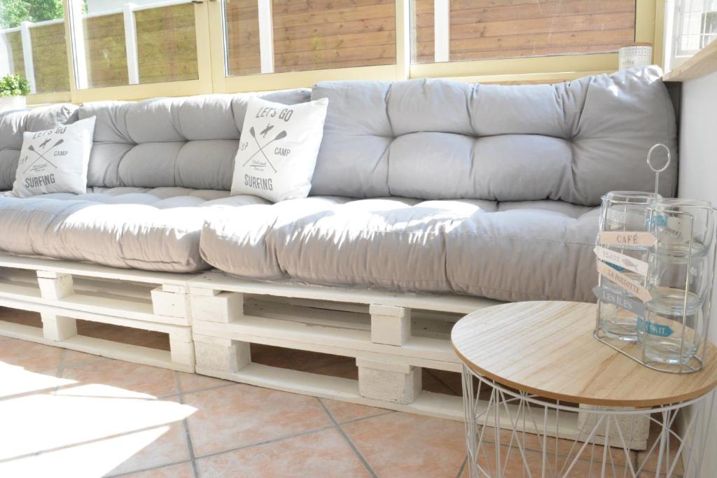 un canapé blanc dans un salon avec une table dans l'établissement VILLA FLEUR DES PINS - 2 CHAMBRES - 3 étoiles BANC D ARGUIN, à Gujan-Mestras