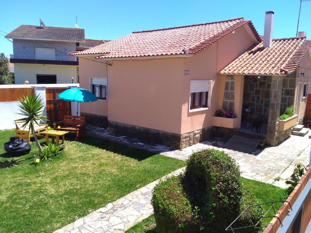ein kleines Haus mit einem grünen Hof mit Sonnenschirm in der Unterkunft Beach house with garden in Sintra