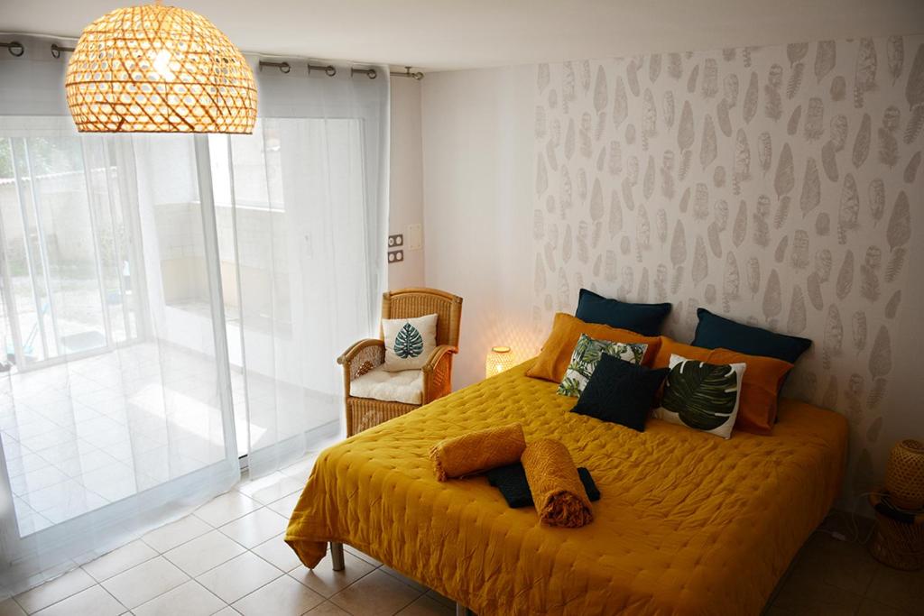 1 dormitorio con cama amarilla y ventana grande en L'Oiseau Bleu, en Tournon-sur-Rhône