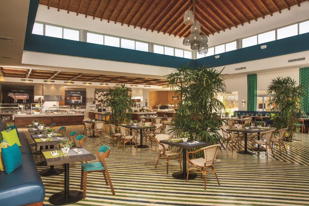 a restaurant with tables and chairs and plants at Dreams Dominicus La Romana Resort & Spa in Bayahibe