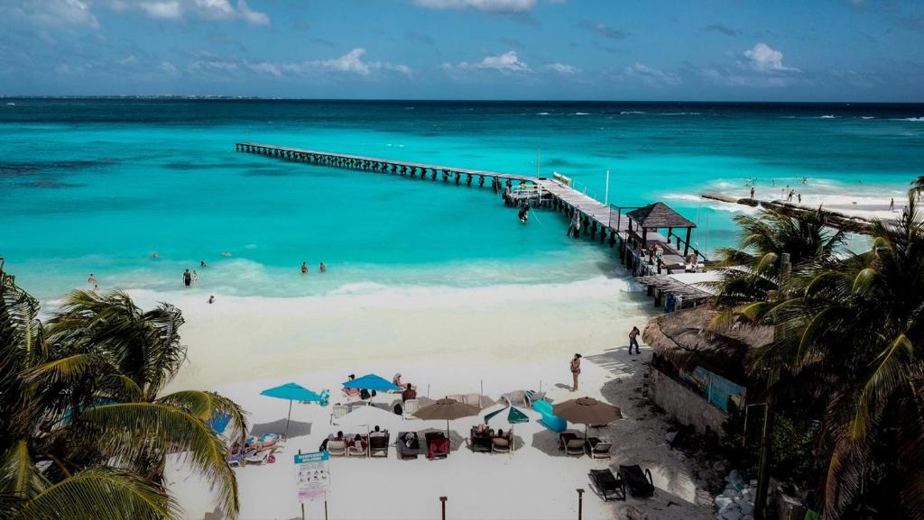 a beach with a pier and people in the water at La Palma Beachfront Hotel & Club Nautico in Cancún