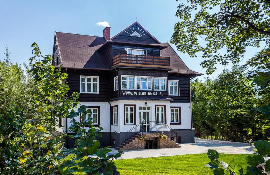 een groot zwart-wit huis met een veranda bij Willa Bianka Szczyrk in Szczyrk