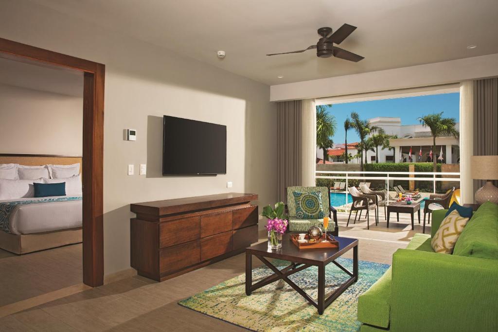 a living room with a green couch and a television at Dreams Dominicus La Romana Resort & Spa in Bayahibe