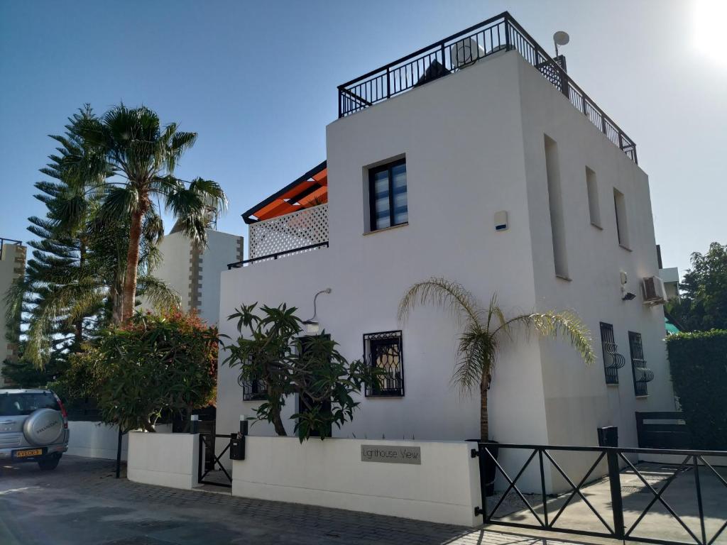 een wit gebouw met palmbomen ervoor bij LightHouse View Villa in Paphos City