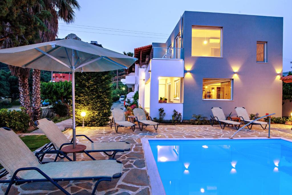 uma piscina com cadeiras e um guarda-sol ao lado de uma casa em IRIDA Guesthouse by the Pool em Plakiás