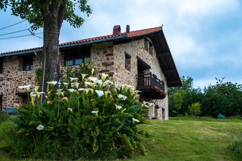 Una casa de piedra con flores delante de ella. en Apartamentos Rurales Larrago, en Busturia