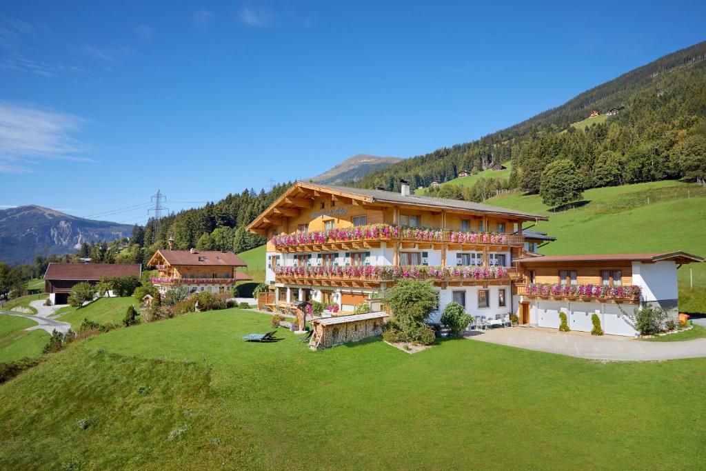 een groot huis op een heuvel met een groen veld bij Hotel Gasthof Abelhof in Neukirchen am Großvenediger