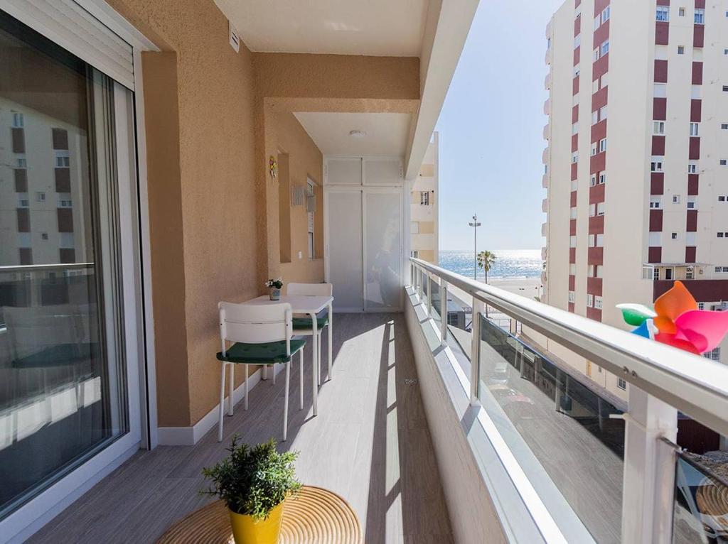 uma varanda com uma mesa e cadeiras num edifício em Victoria - Apartamento Playa em Cádiz