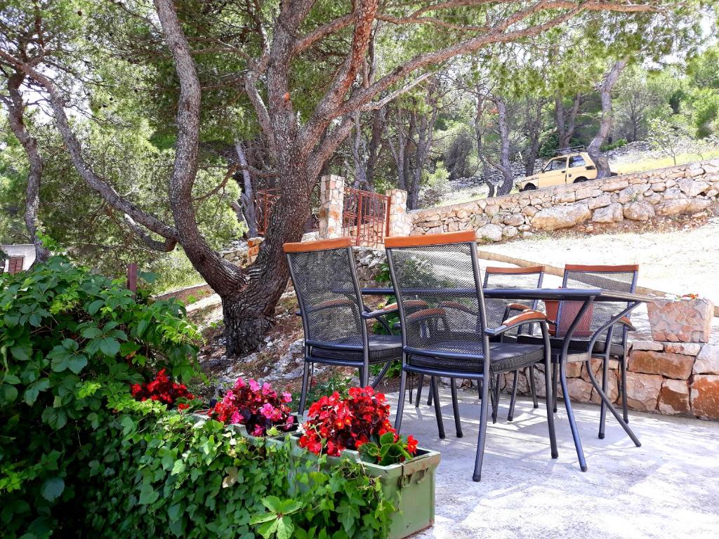 una mesa, sillas y flores en un patio en Apartment Teuta, en Isla Žirje