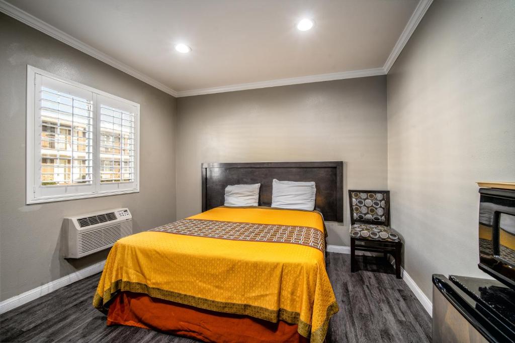 een slaapkamer met een bed met een gele deken bij Regency Inn & Suites Downey in Downey