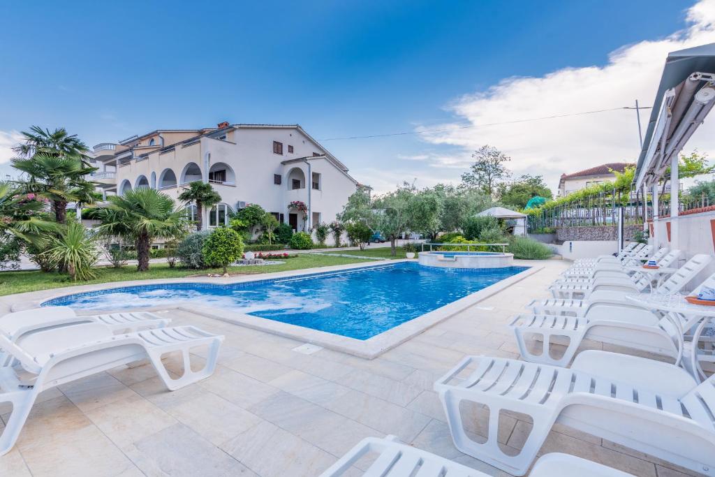 a villa with a swimming pool and lounge chairs at B&B Dujmović in Malinska