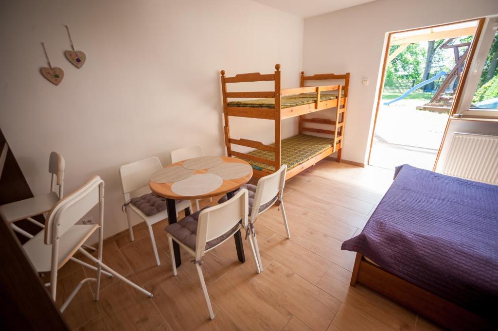 Zimmer mit einem Tisch, Stühlen und einem Etagenbett in der Unterkunft U Jarka in Smołdziński Las