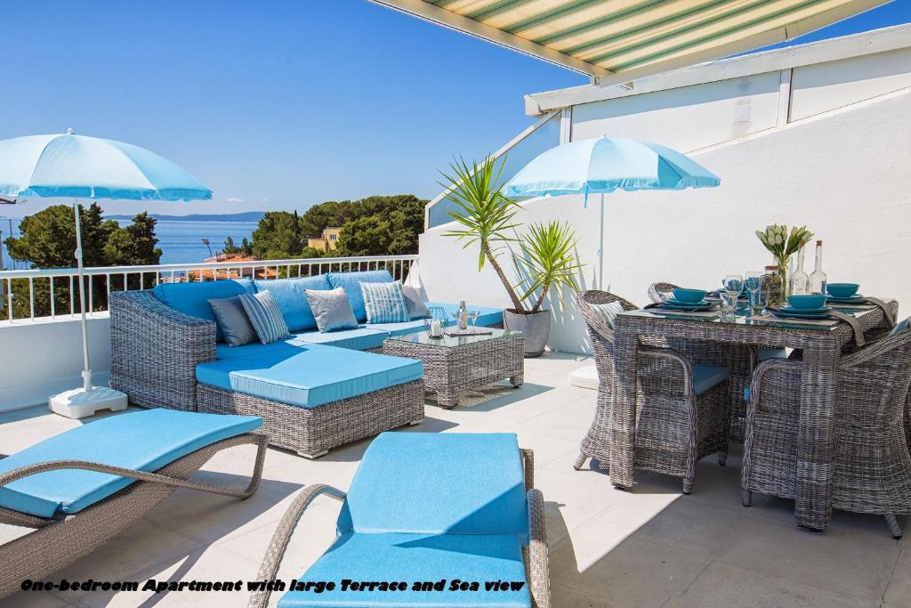 une terrasse avec des chaises bleues, une table et des parasols dans l'établissement Holiday Apartments Split, à Split
