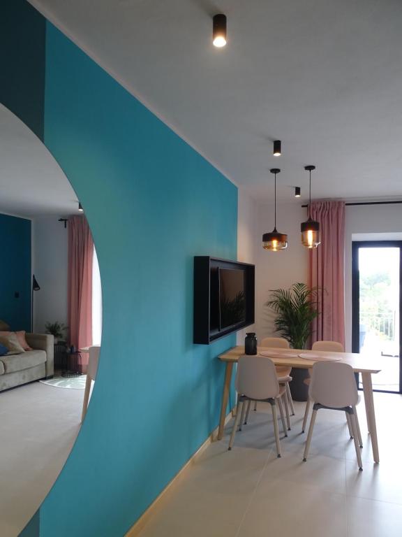 salon ze stołem i niebieską ścianą w obiekcie Apartments Pržina w mieście Lumbarda
