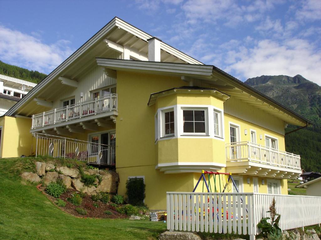 a yellow house with a white fence in front of it at Appartement Arnika in Sölden