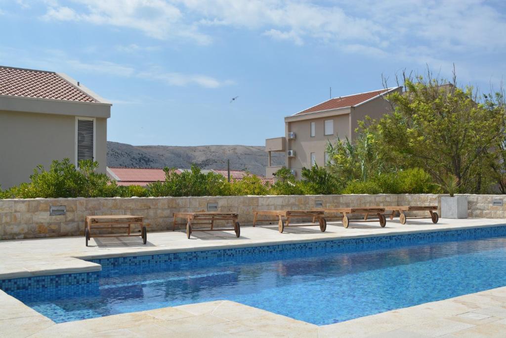 a swimming pool with benches next to a building at Villa Antea - modern house with pool in Pag