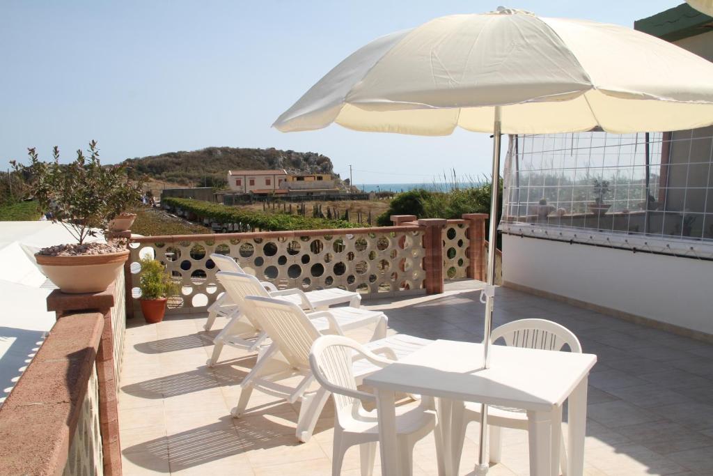 a patio with white chairs and an umbrella at B&B Giarrizzo in Licata