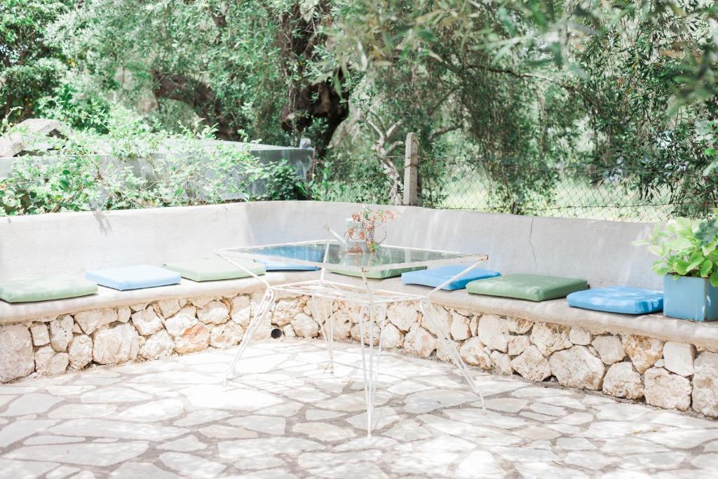 a stone bench with a glass table and stools at Afroditi Pansion in Agios Nikitas