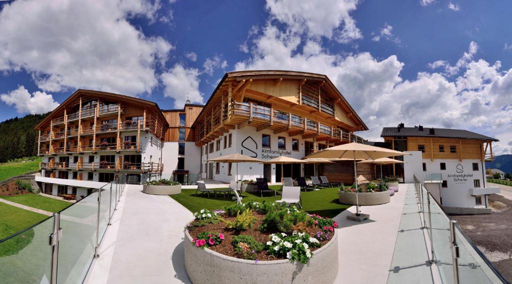 a large building with a courtyard with tables and umbrellas at Almfamilyhotel Scherer in Obertilliach