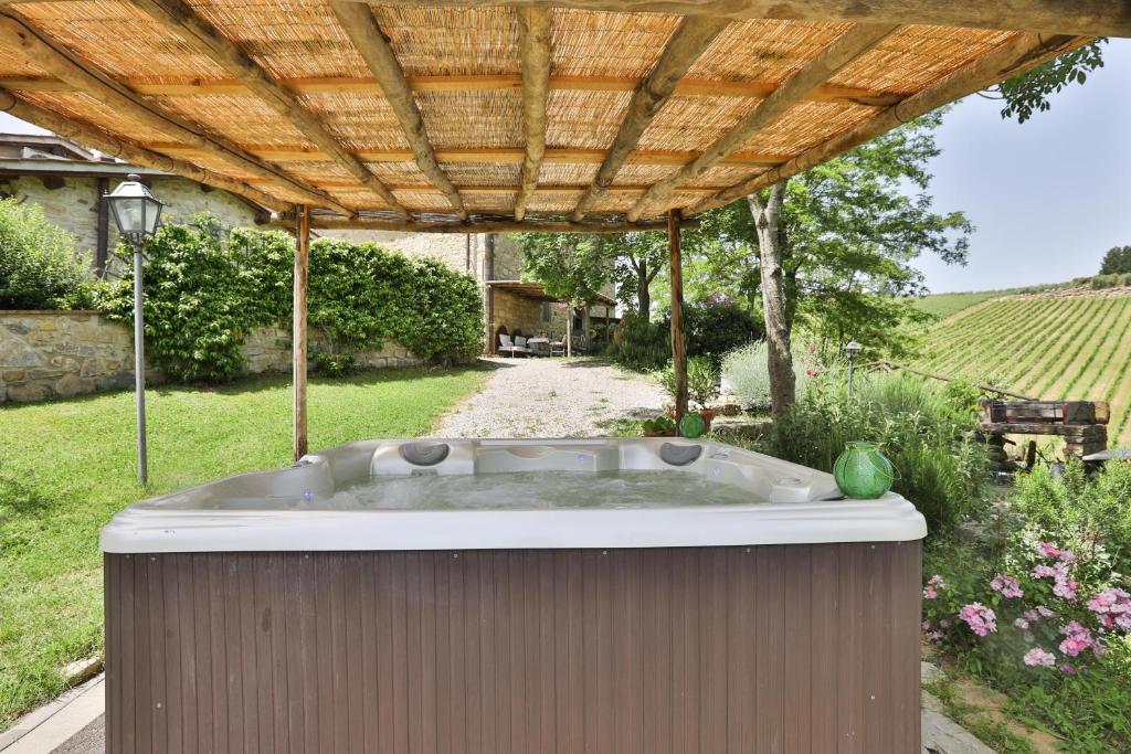 a hot tub in a yard with a wooden pergola at Il Vichiaccio Country House in Impruneta