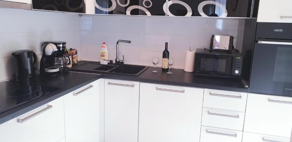a kitchen with white cabinets and a microwave and a sink at Apartment Kiki in Kotor