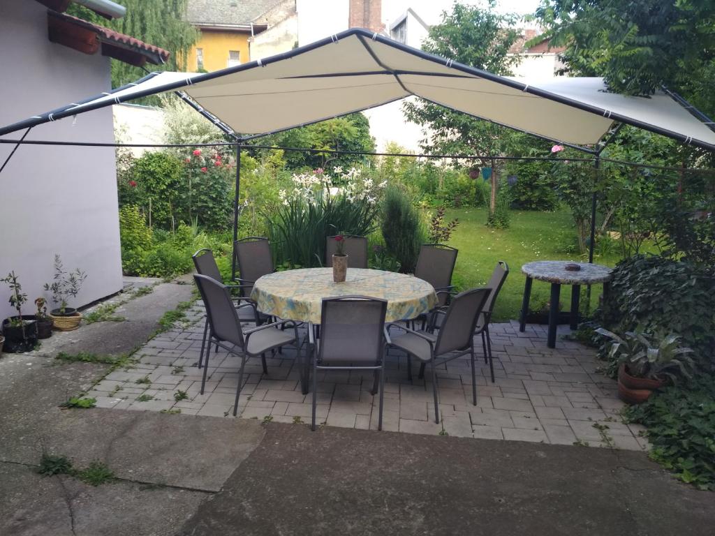 um pátio com uma mesa, cadeiras e um guarda-sol em Apartman Lux em Szeged