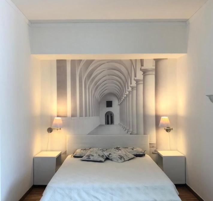 ein Schlafzimmer mit einem weißen Bett und zwei Nachttischen in der Unterkunft Eva's house Roma in Rom