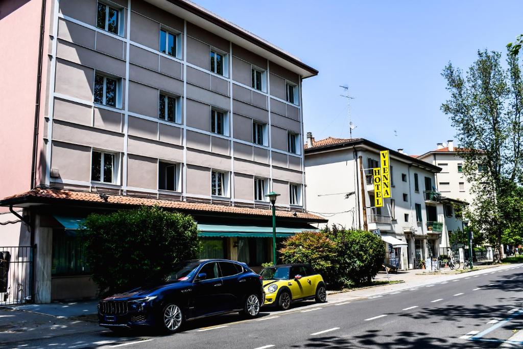 two cars parked in front of a building on a street at Hotel Vienna in Marghera