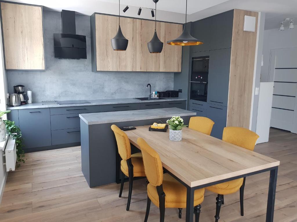 eine Küche mit einem Holztisch und gelben Stühlen in der Unterkunft Luksusowe Apartamenty na Toruńskiej in Kwidzyn