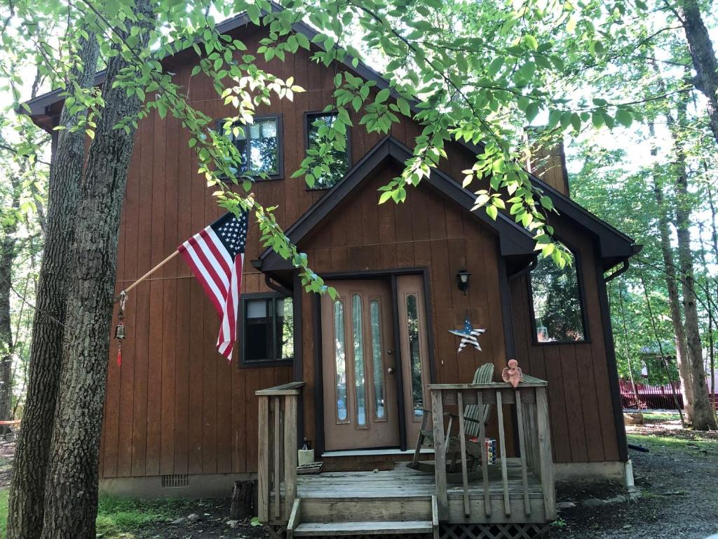 ein kleines Haus im Wald mit amerikanischer Flagge in der Unterkunft My Little Flagship Cabin in East Stroudsburg